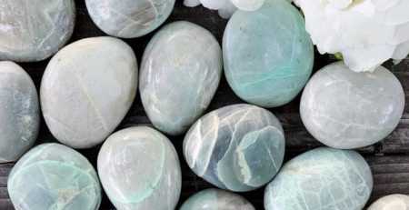 A bunch of green and white stones on a wooden table.