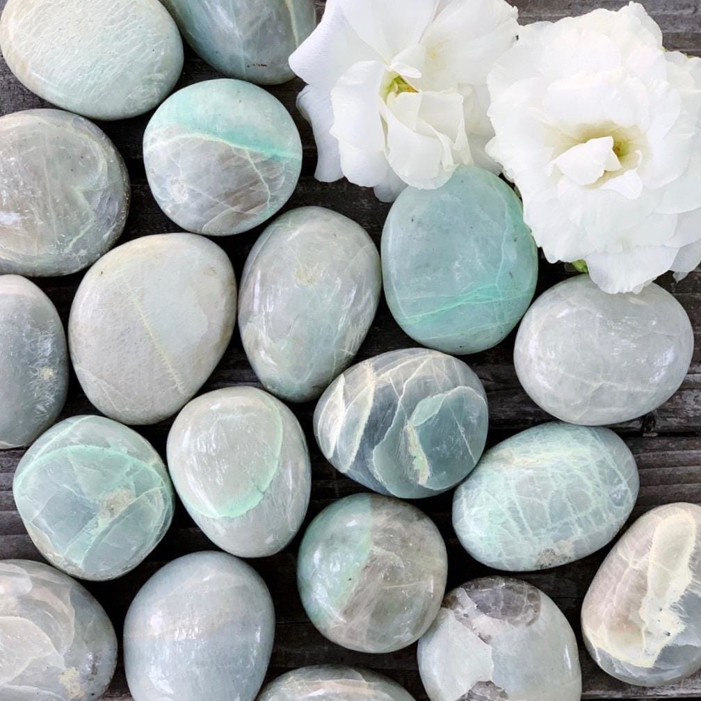 A bunch of green and white stones on a wooden table.