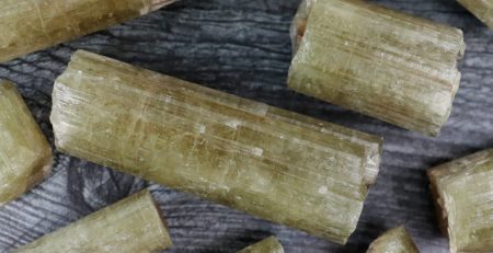 A bunch of green crystals on a wooden table.