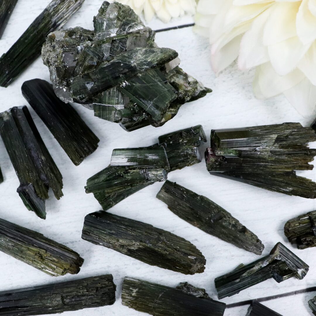 A bunch of black tourmaline crystals on a white surface.