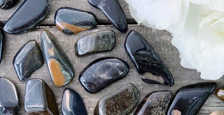 A bunch of stones and flowers on a wooden table.