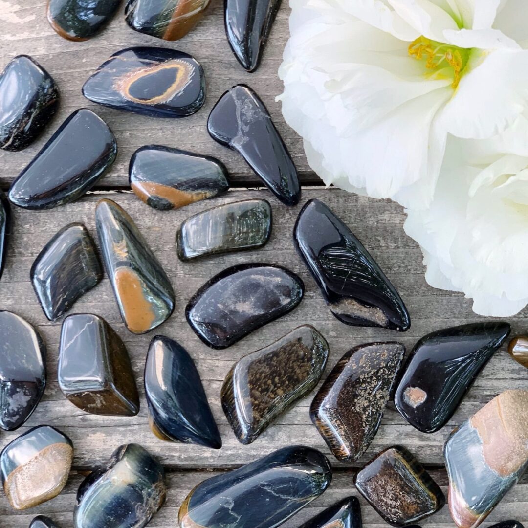 A bunch of stones and flowers on a wooden table.