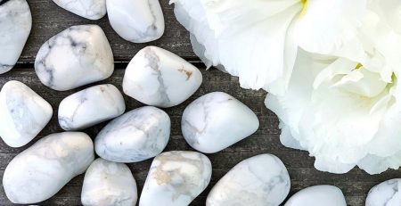 White marble pebbles and a white flower on a wooden table.