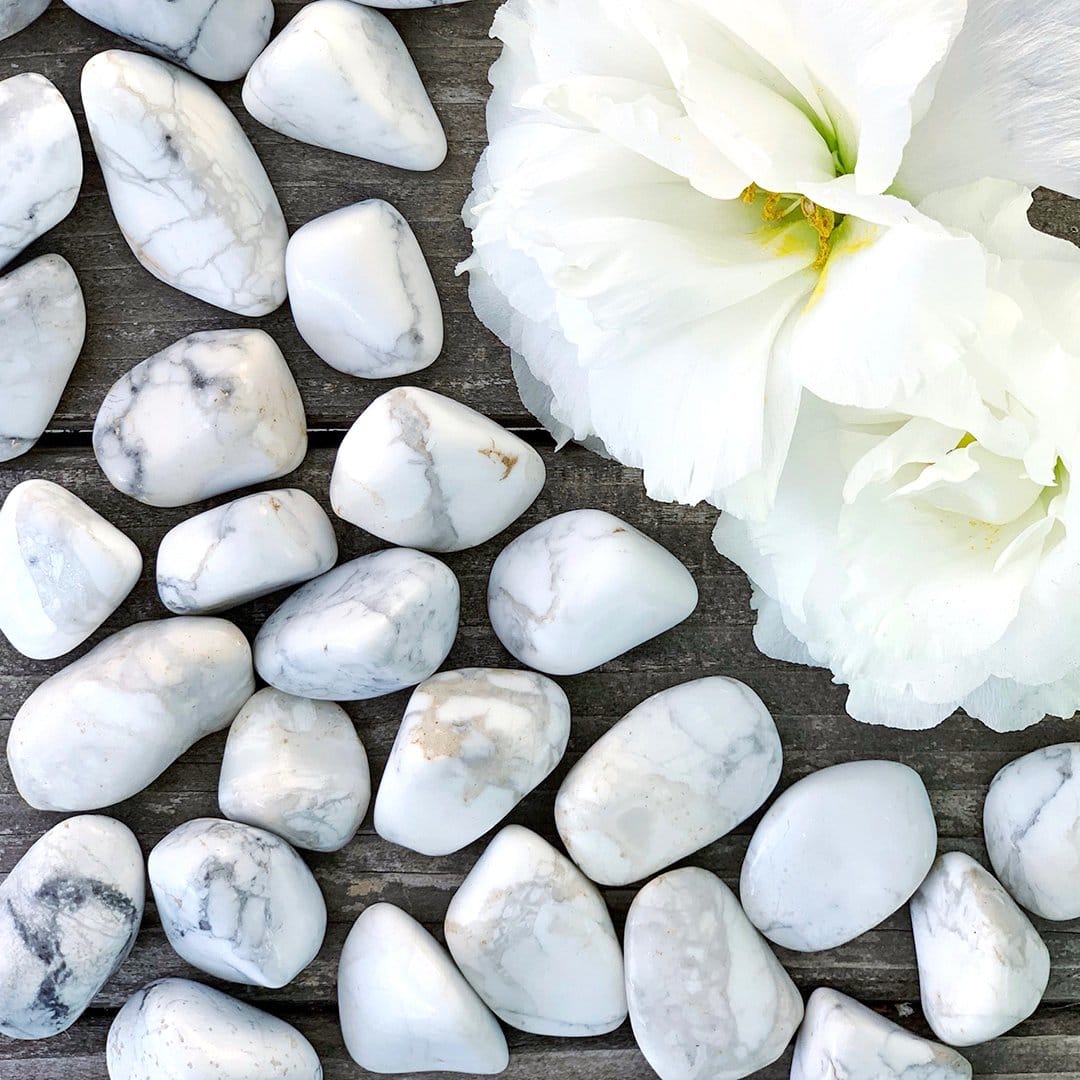 White marble pebbles and a white flower on a wooden table.