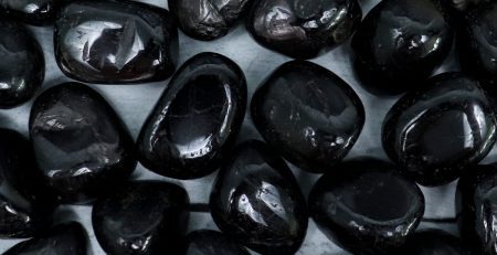 A pile of black pebbles on a white surface.