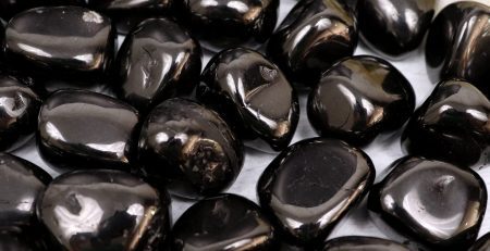 Black pebbles on a table next to a flower.