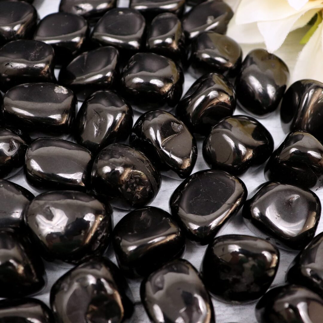 Black pebbles on a table next to a flower.