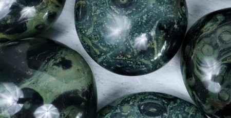 A group of green and black marbles on a white surface.