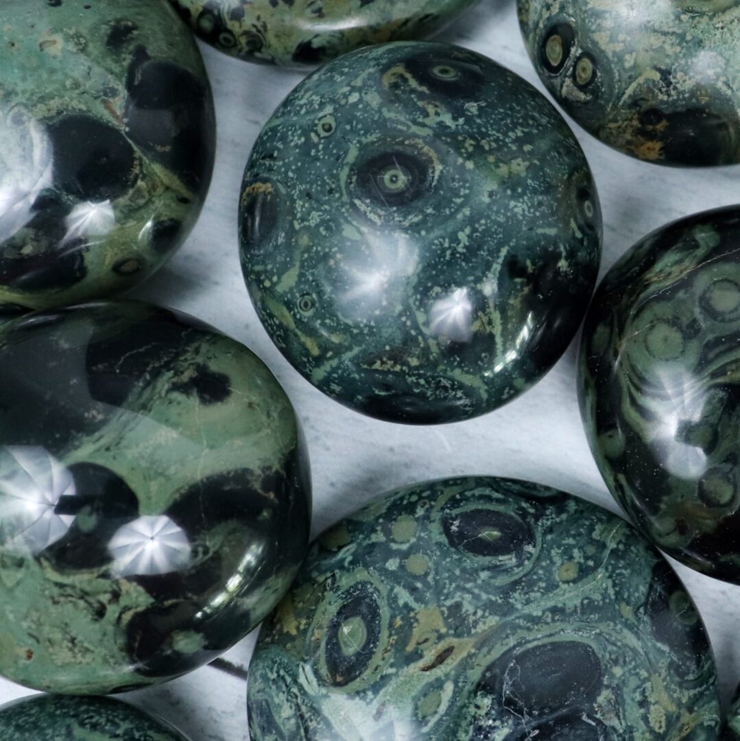 A group of green and black marbles on a white surface.