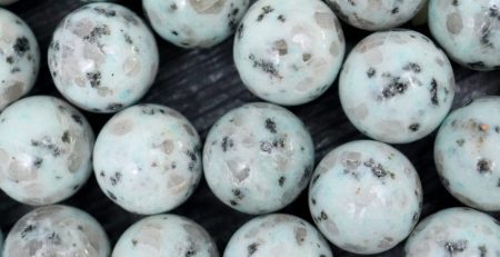 A bunch of green and black marble beads on a table.