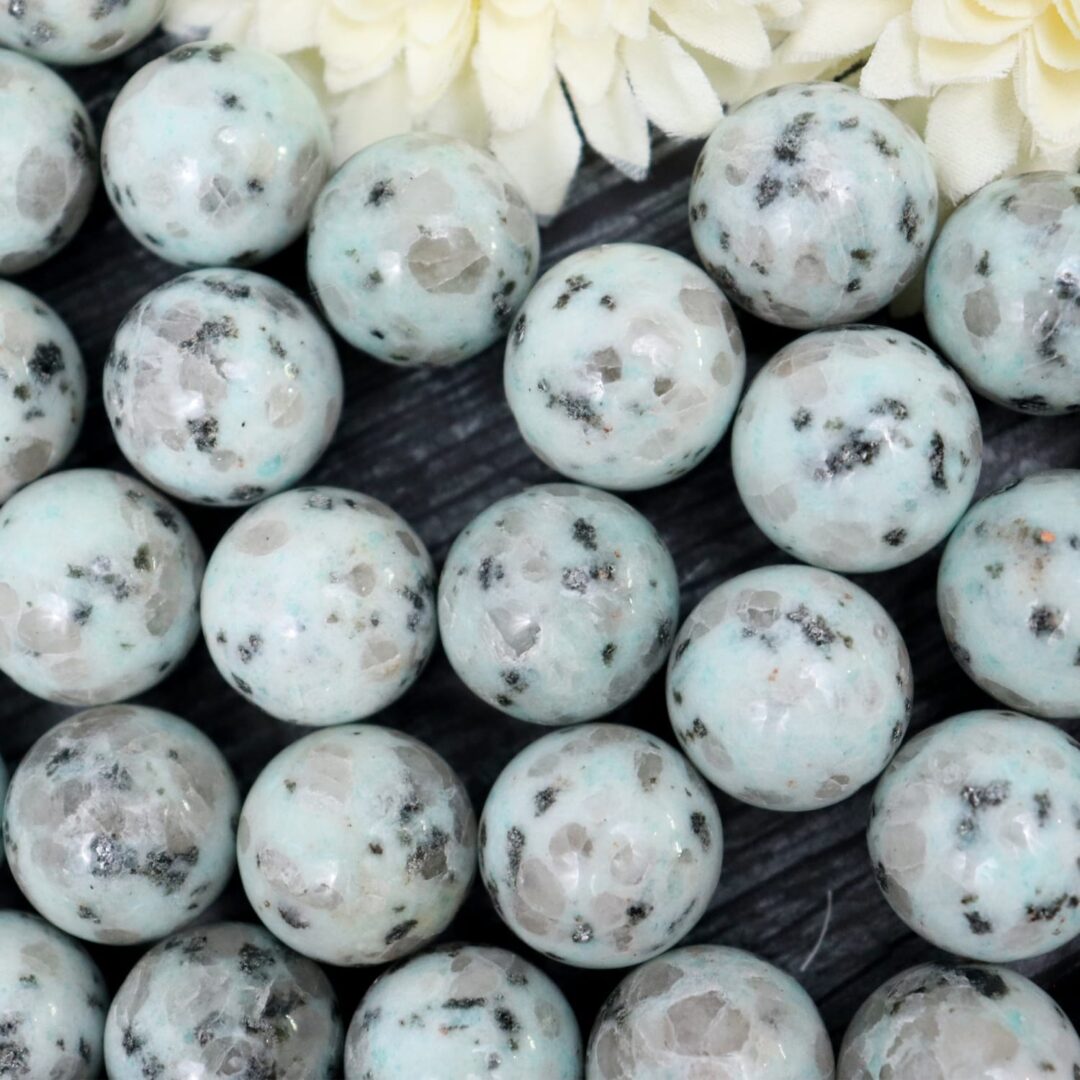 A bunch of green and black marble beads on a table.