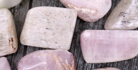 A bunch of pink and white stones on a wooden table.