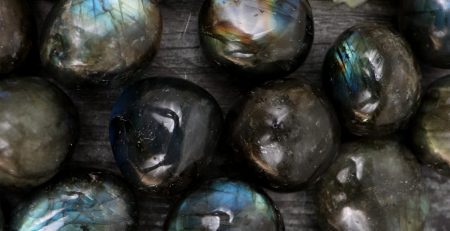 A bunch of labradorite beads on a wooden surface.