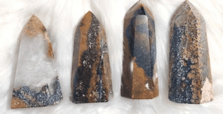 Four tiger eye quartz points on a white furry surface.