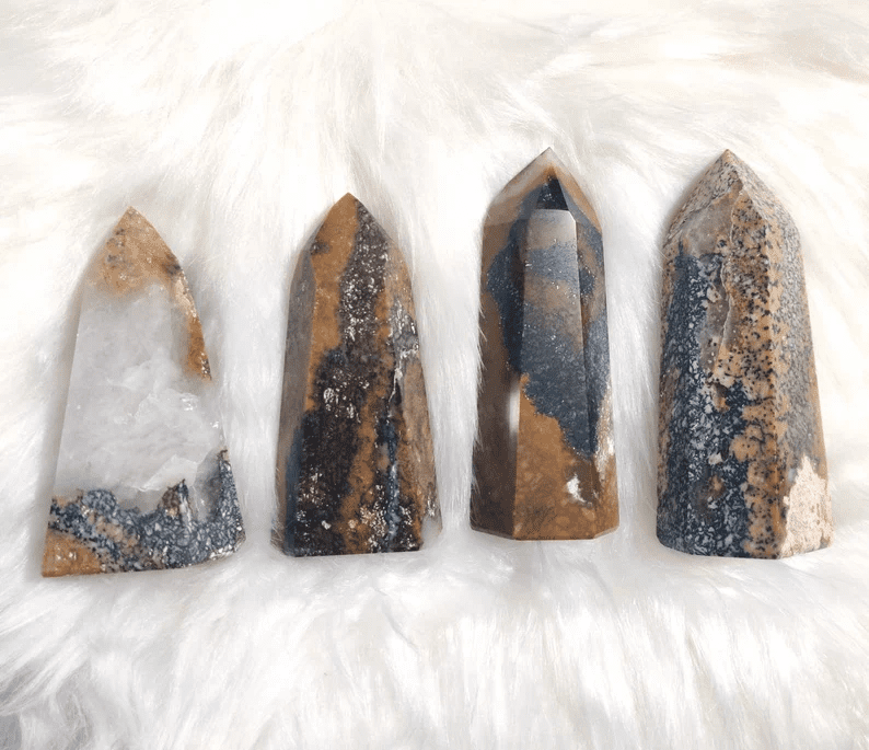 Four tiger eye quartz points on a white furry surface.