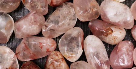 A pile of pink quartz stones on a wooden surface.