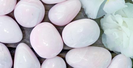 A bunch of pink stones and flowers on a wooden table.