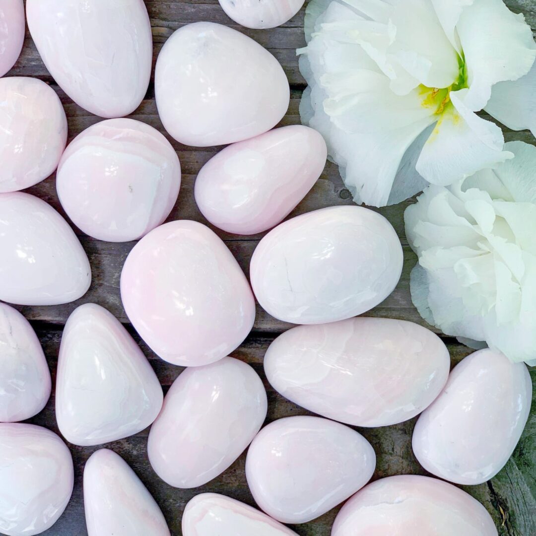 A bunch of pink stones and flowers on a wooden table.