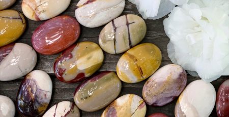 A bunch of marbles and flowers on a wooden table.