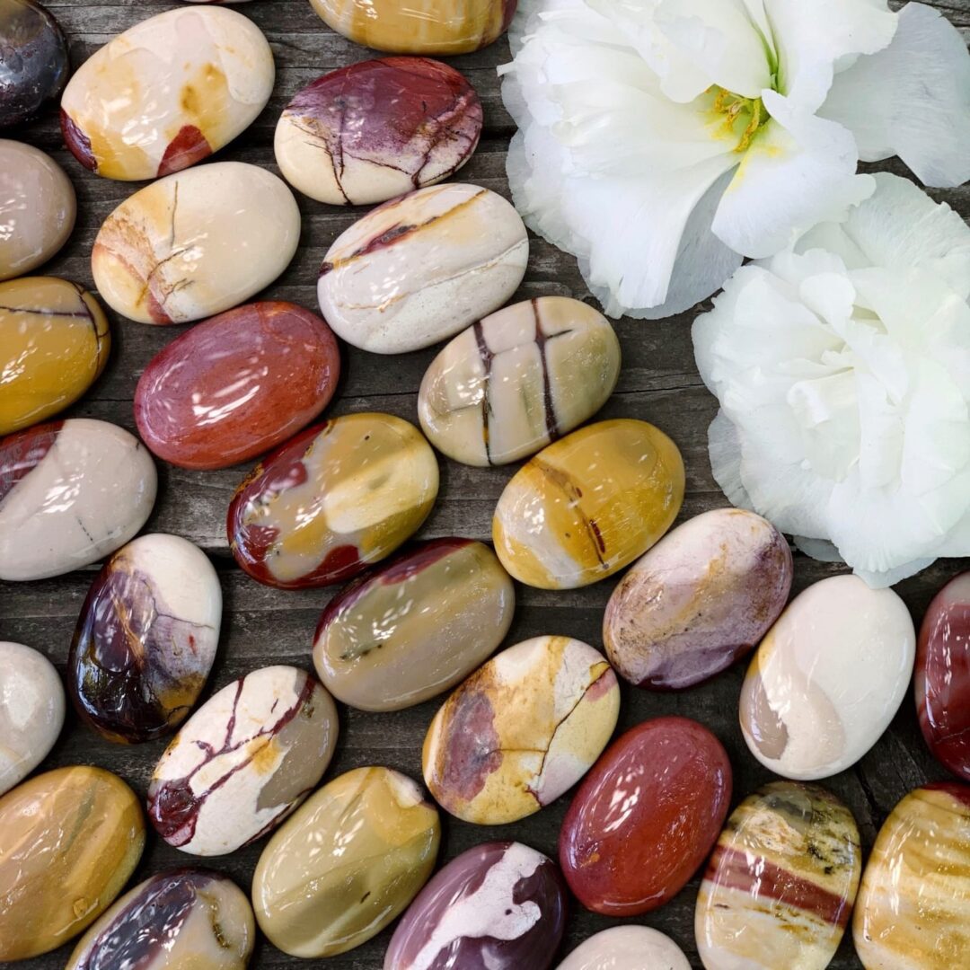 A bunch of marbles and flowers on a wooden table.