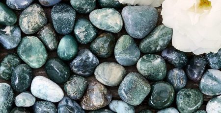 A bunch of green and white stones with a flower in the middle.