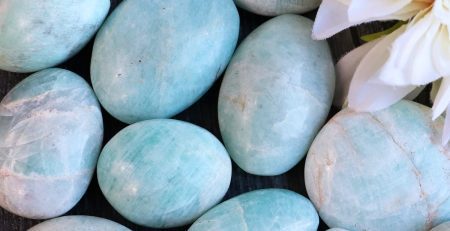 Aquamarine pebbles with a flower on a wooden table.