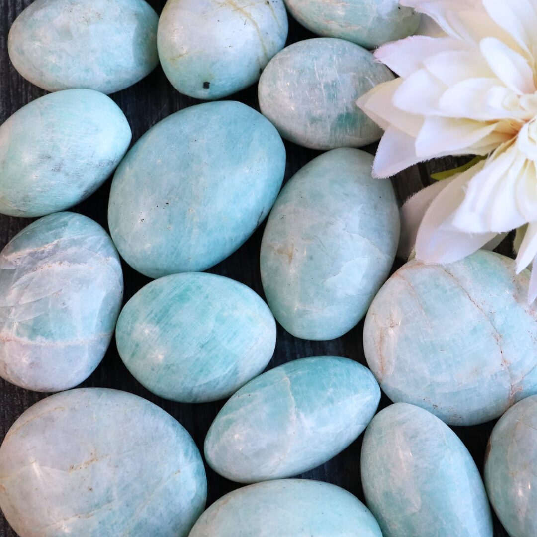 Aquamarine pebbles with a flower on a wooden table.