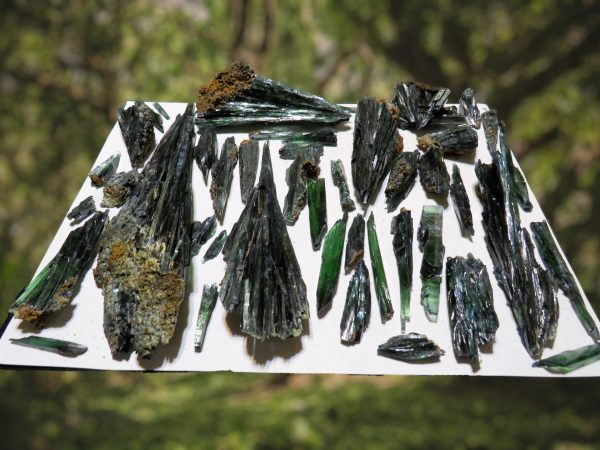 Green and black gemstone crystals on white paper.