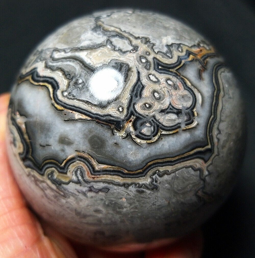 A black and gray agate ball in a person's hand.