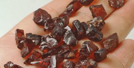 A person holding a handful of brown crystals in their hand.