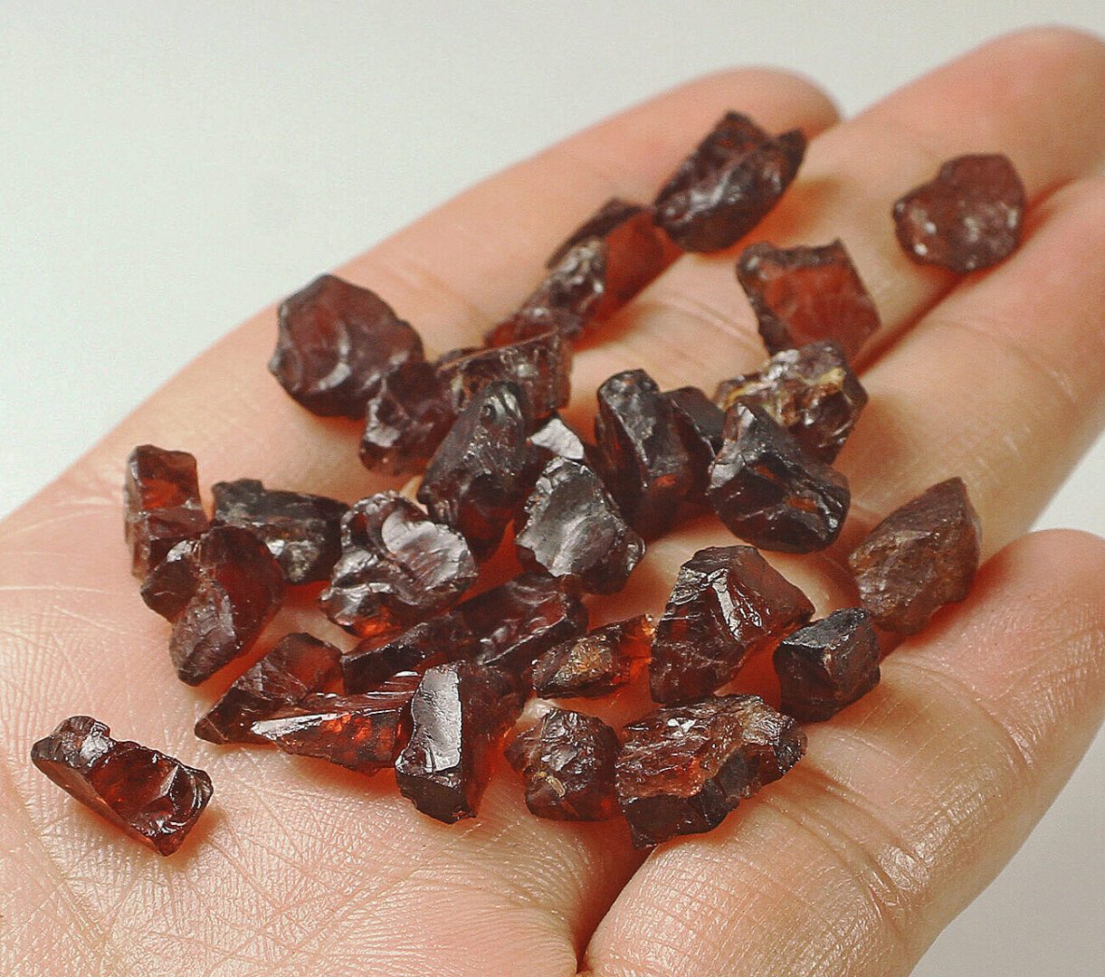 A person holding a handful of brown crystals in their hand.