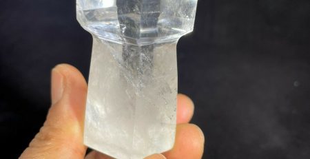 A person holding a small piece of clear quartz.