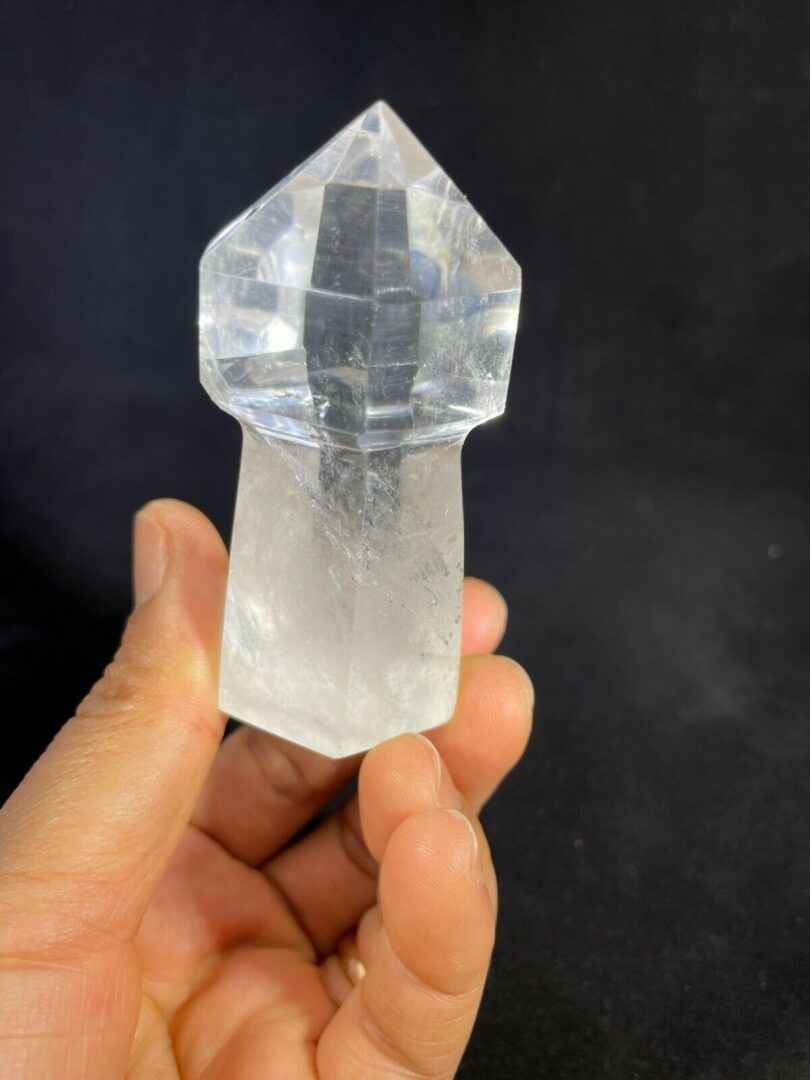 A person holding a small piece of clear quartz.