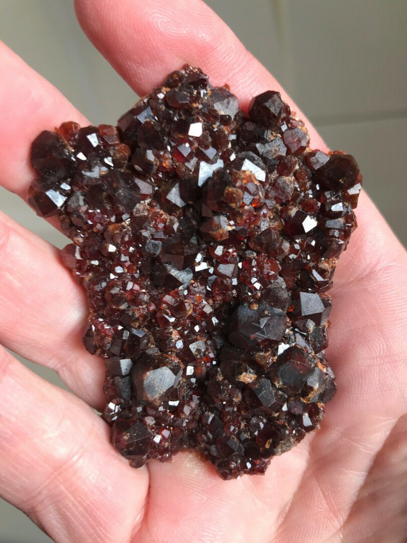 A person holding a piece of red garnet in their hand.