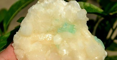 A person holding a piece of white and green quartz.