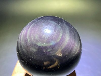A black and purple crystal ball on a wooden base.