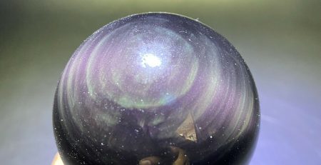 A black and purple crystal ball on a wooden base.