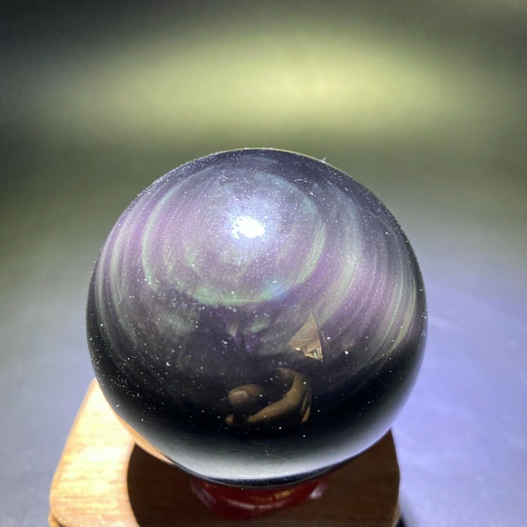 A black and purple crystal ball on a wooden base.