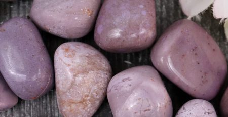 A bunch of purple stones on a wooden table.