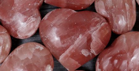 A bunch of pink heart shaped quartz crystals on a table.