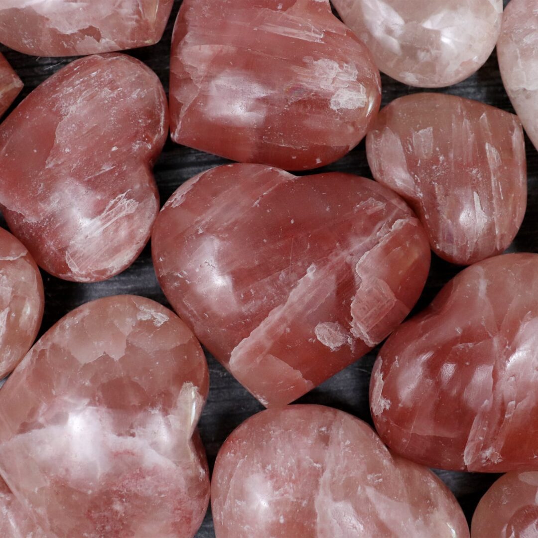 A bunch of pink heart shaped quartz crystals on a table.