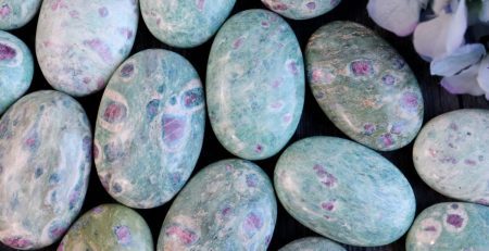 A bunch of green and purple marble eggs on a table.