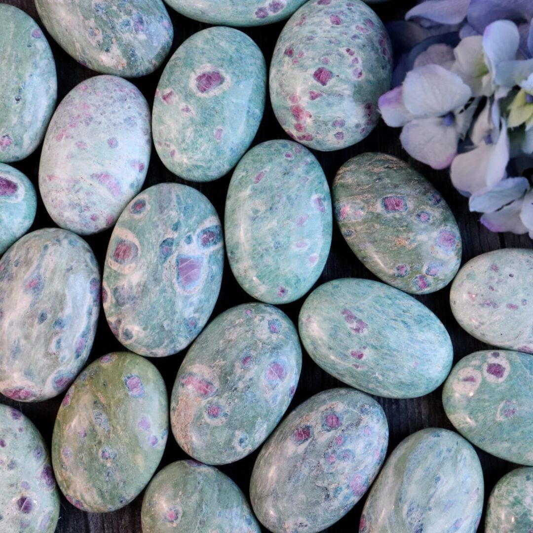 A bunch of green and purple marble eggs on a table.