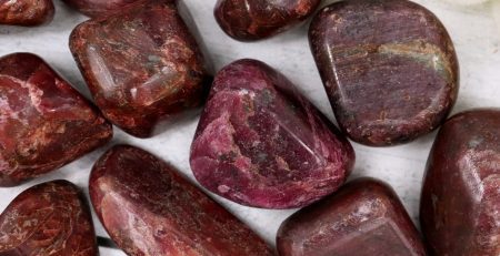 A bunch of red ruby stones on a white surface.