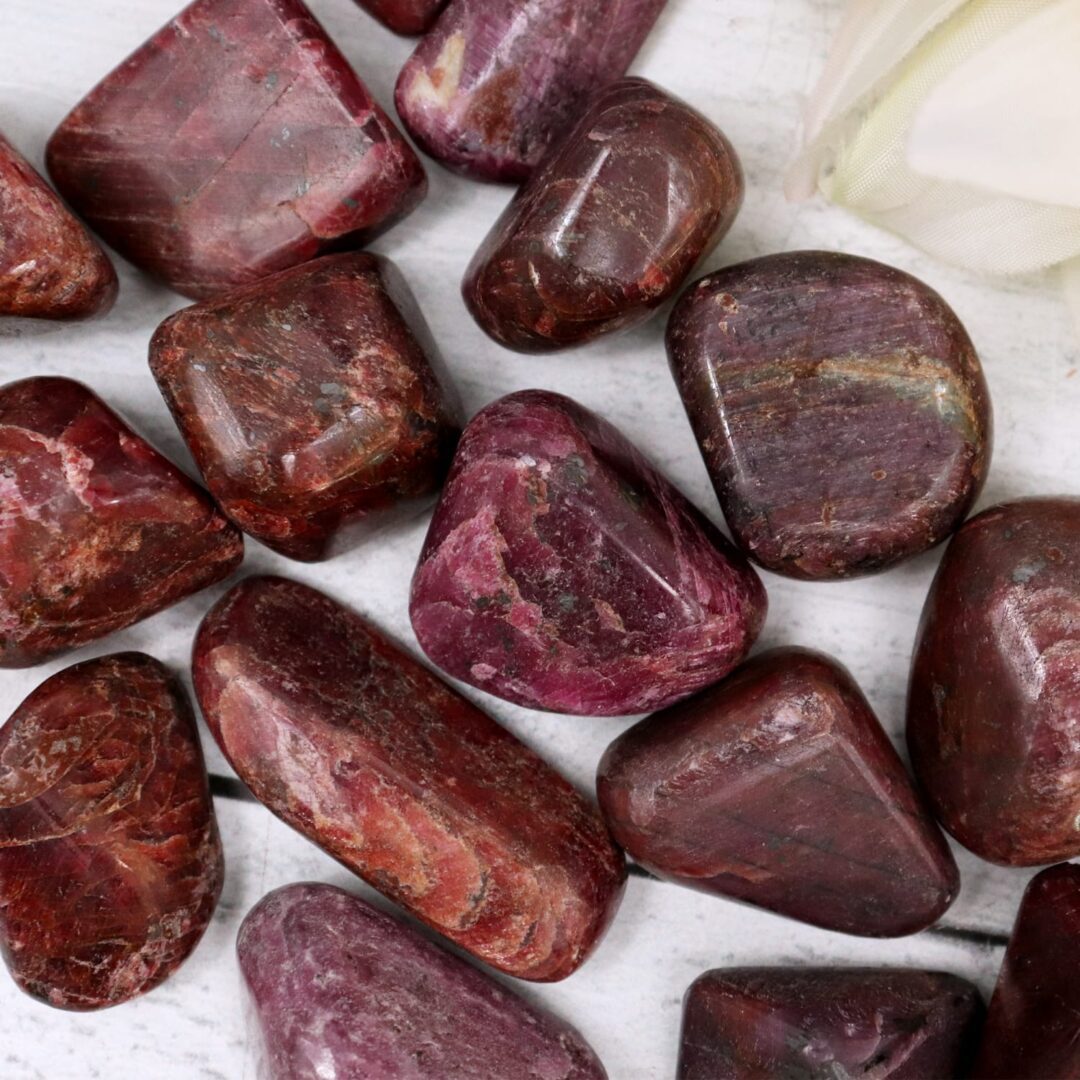 A bunch of red ruby stones on a white surface.