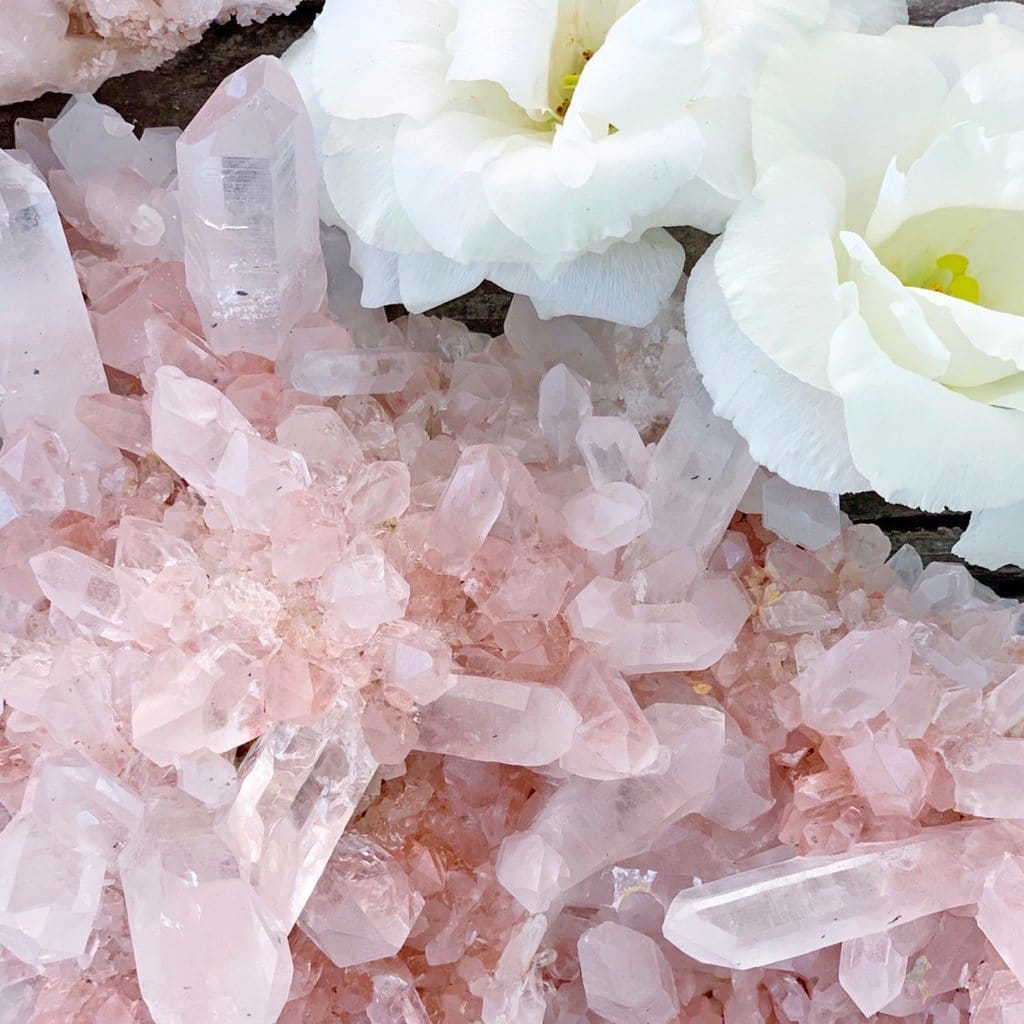 A bunch of rose quartz crystals and white flowers.