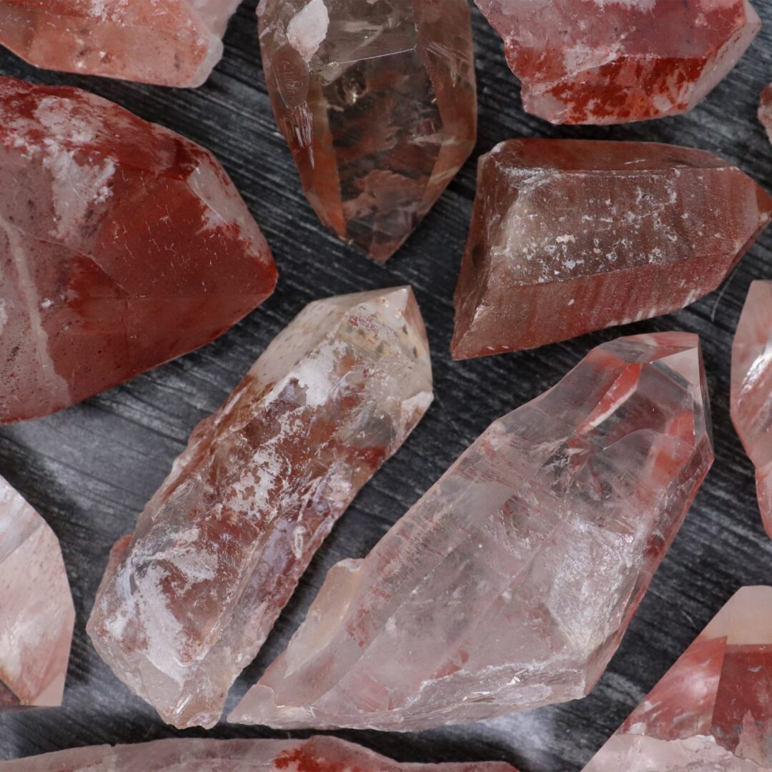 A group of pink and red quartz crystals on a dark surface.