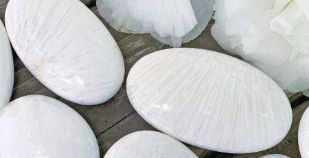 White pebbles and flowers on a wooden table.