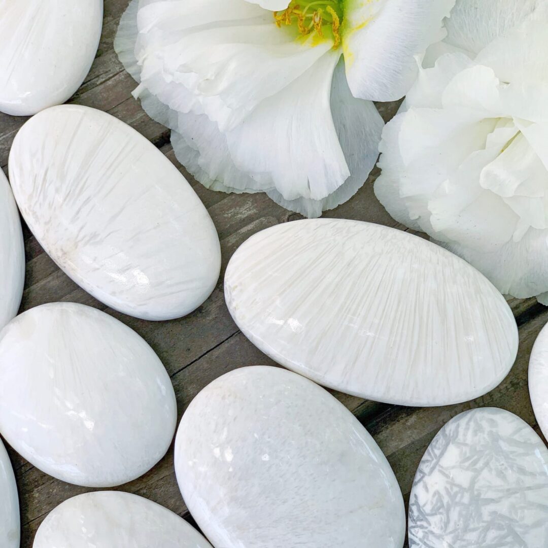 White pebbles and flowers on a wooden table.