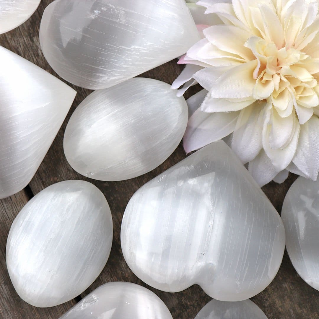 A bunch of white heart shaped quartz crystals on a wooden table.